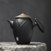 Black teapot with round lid, isolated on gray stone background.