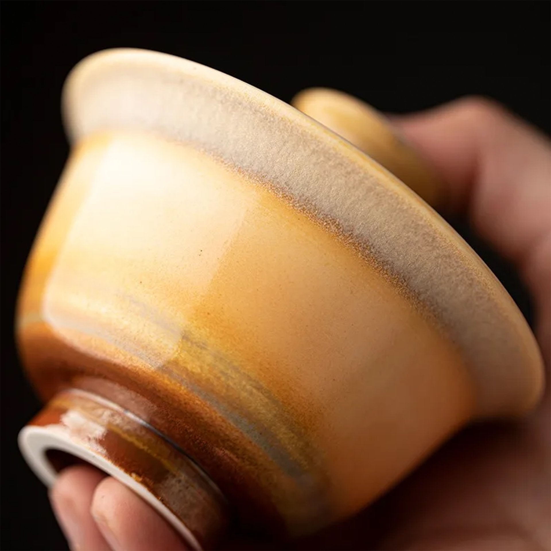 Hand cradling a gaiwan, focusing on its smooth, curved underside.