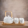 Marble patterned teapot with bamboo handle and matching cups on a wooden tray.