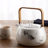 Marble-patterned teapot with bamboo handle and cup on a wooden table.