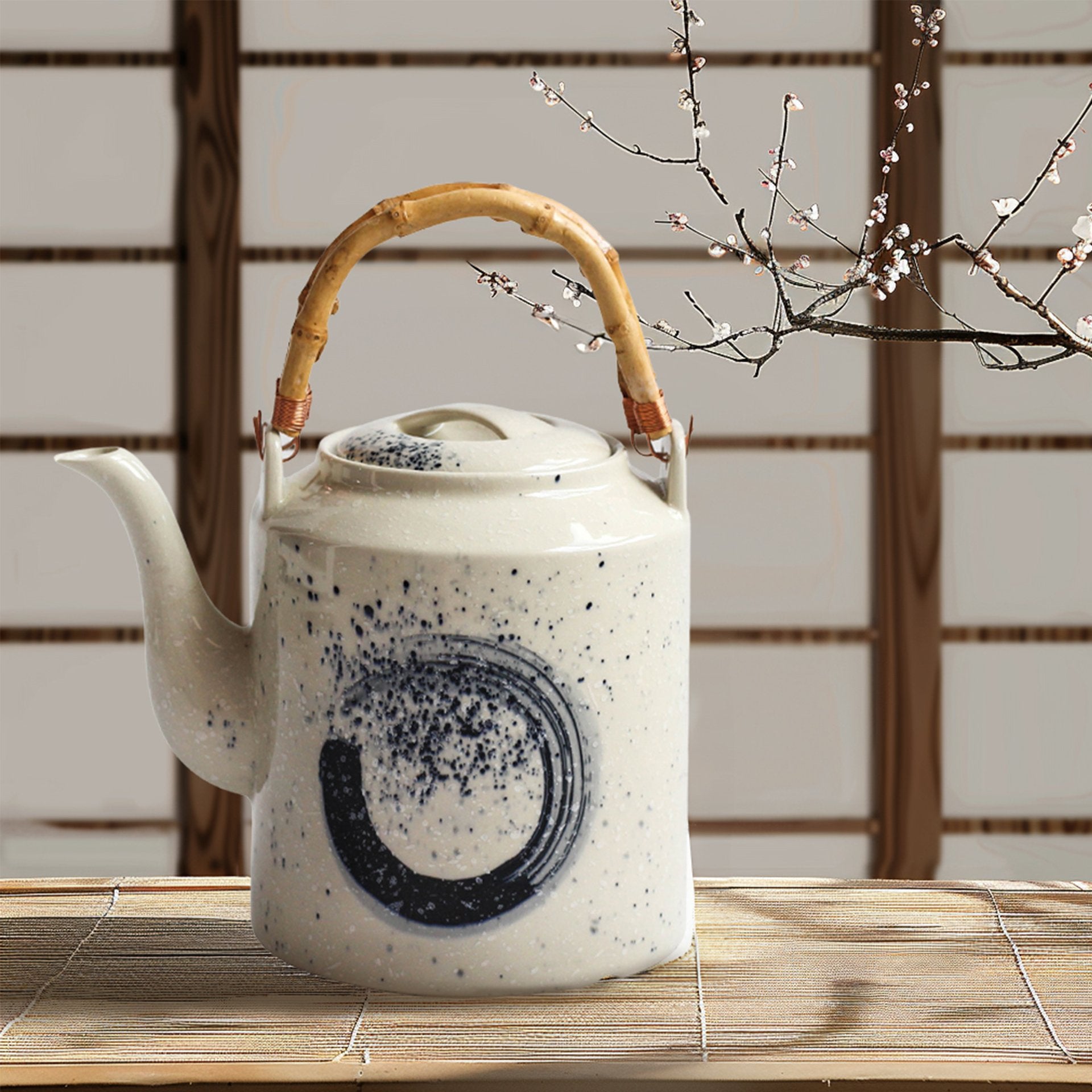 White square teapot with black swirl on a tatami mat with cherry blossoms.