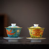 Ornate tea cups, vibrantly painted with traditional Japanese patterns featuring mythical creatures like the phoenix and the dragon, set against rich blue and yellow backgrounds.