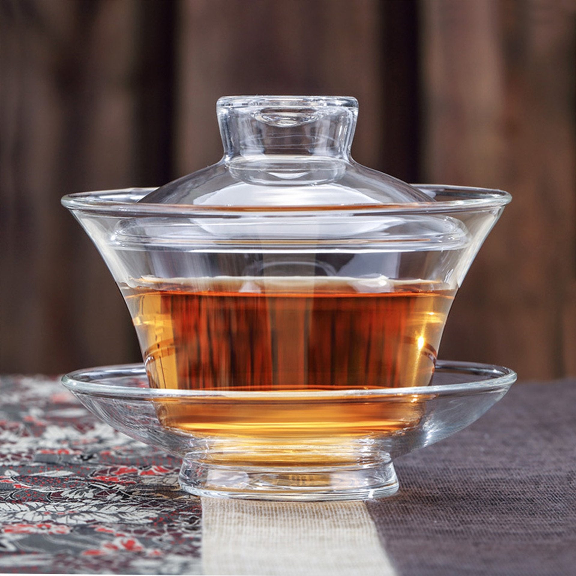 Clear glass gaiwan teapot filled with tea.