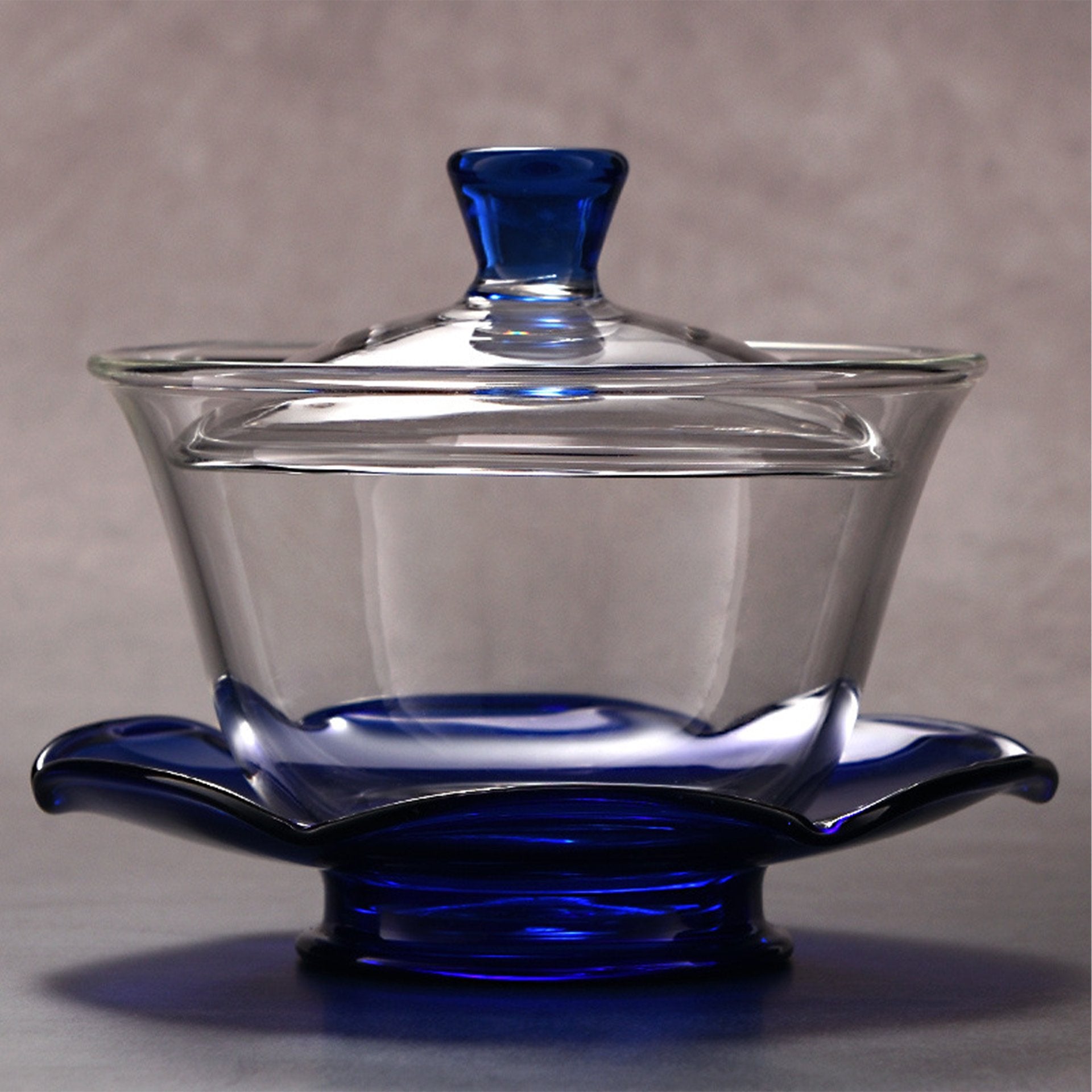 Gaiwan-style glass teapot with blue trim.