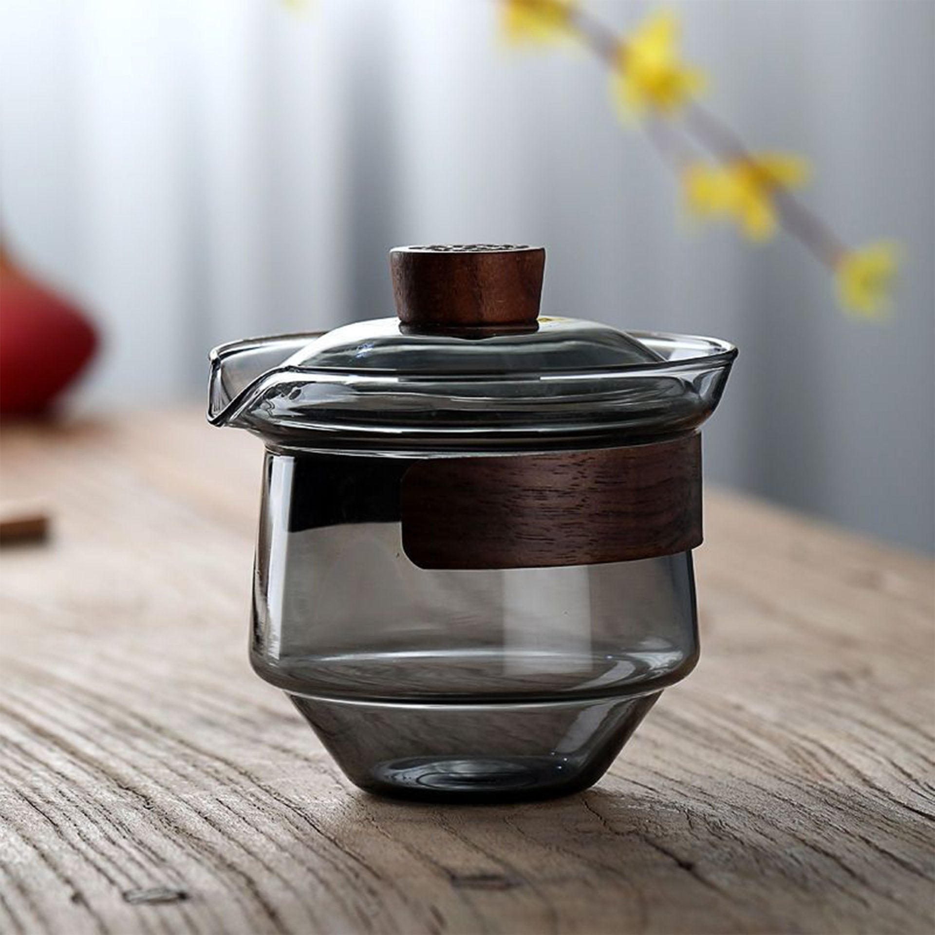 Elegant glass teapot with wooden accents placed on a wooden surface with soft lighting