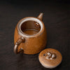 Open brown glazed teapot with built-in strainer, beside its lid with lion detail