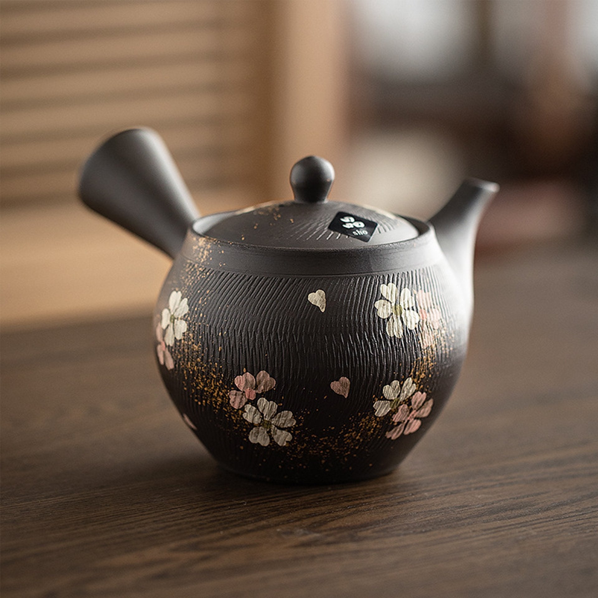 Traditional Japanese teapot with floral motifs displayed on a wooden table.