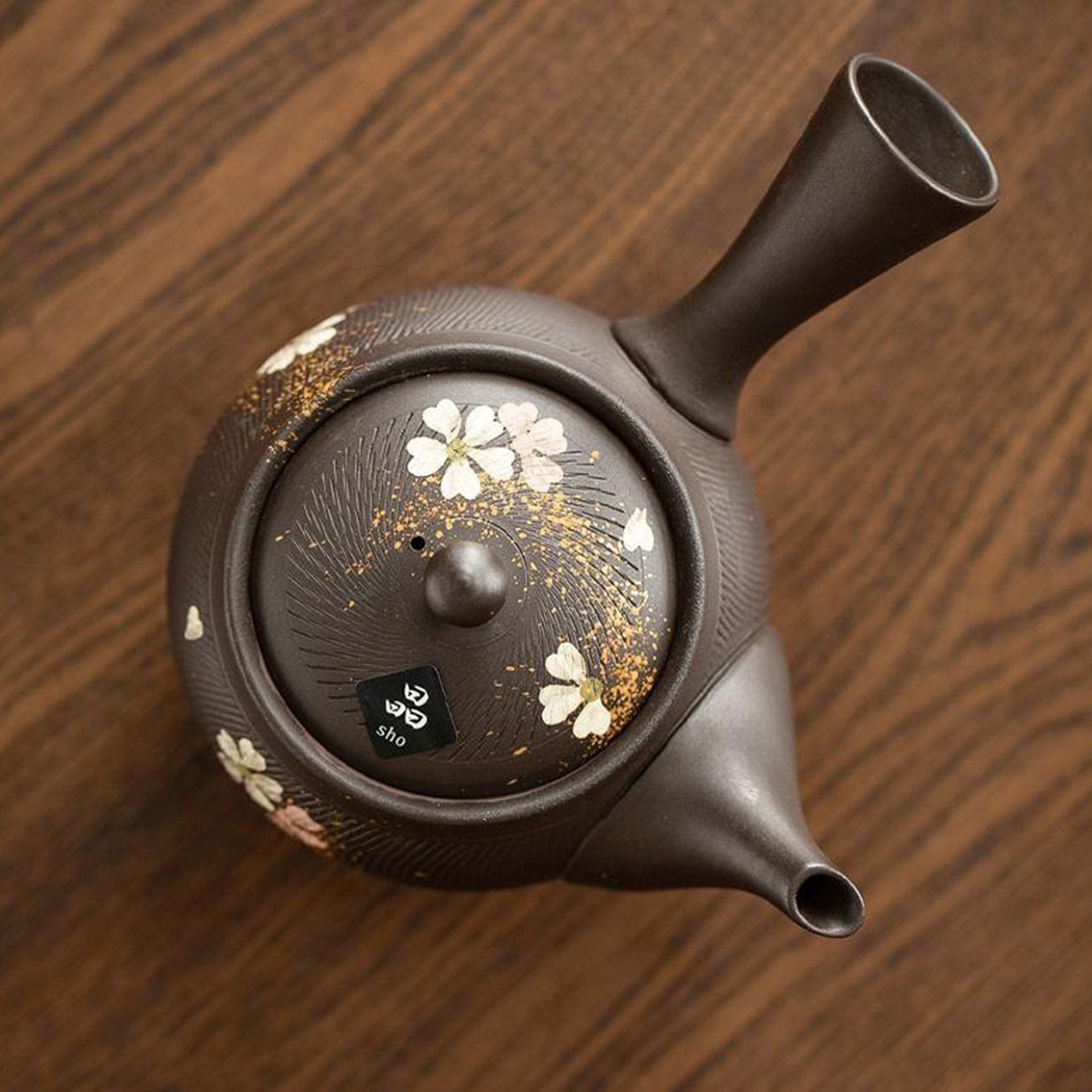 Top view of a dark teapot with floral and gold patterns.
