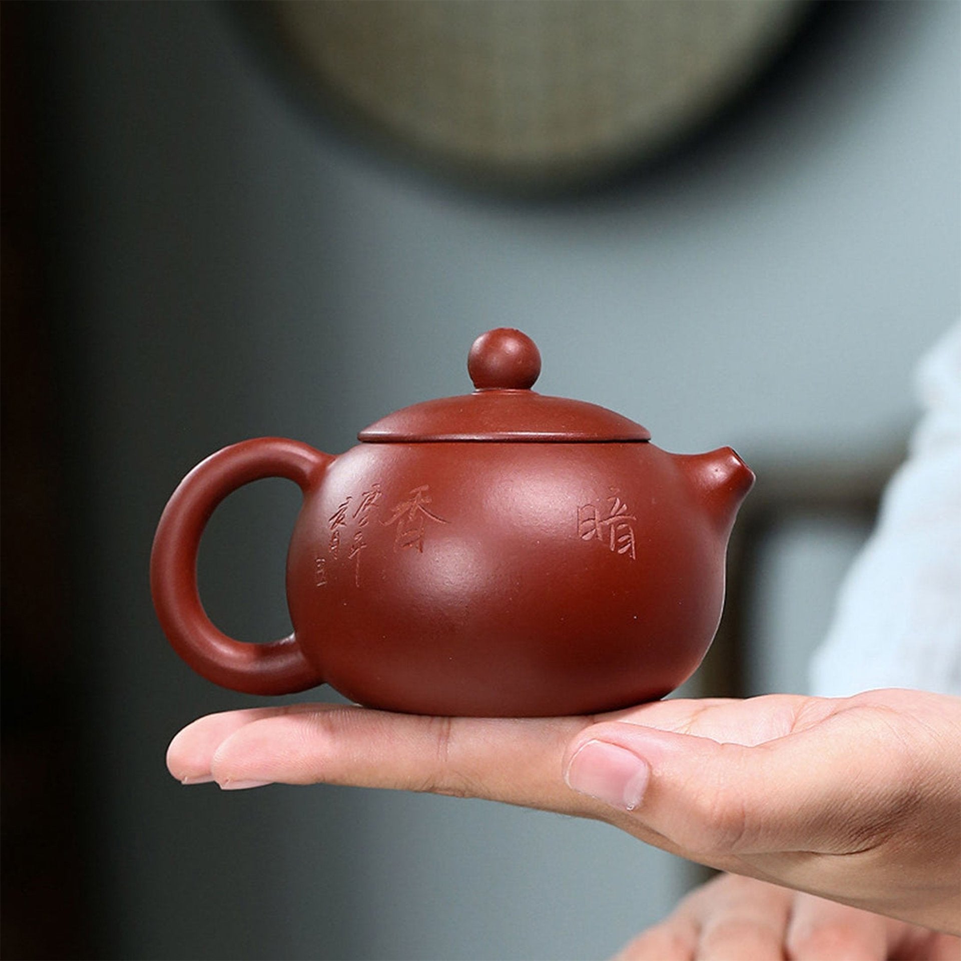 Woman holding a red teapot open, emphasizing the teapot's inner markings and quality.