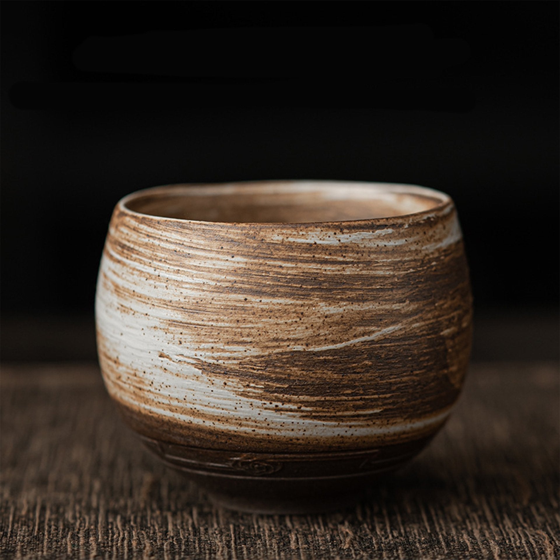 Brown and white striped ceramic tea bowl on wooden surface