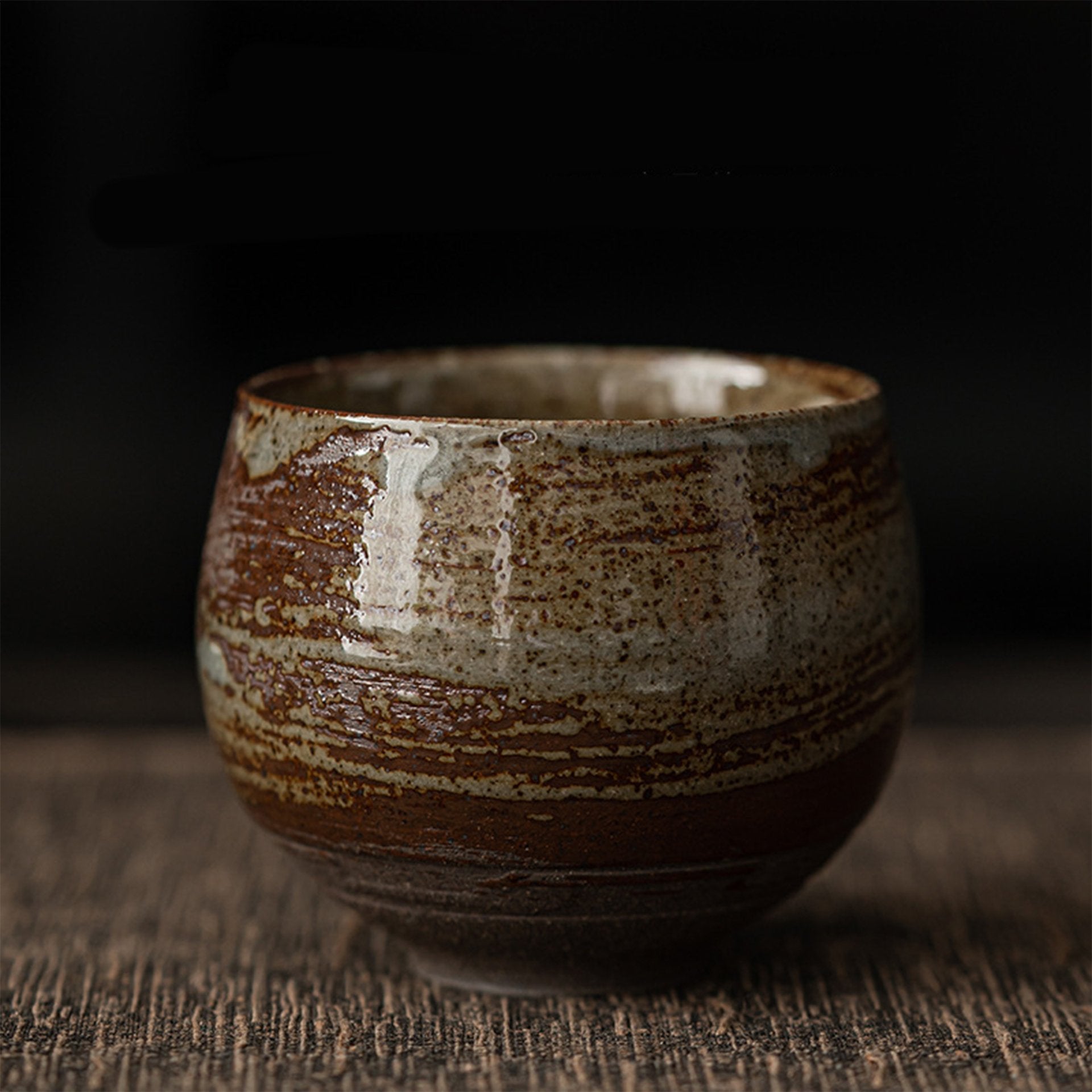 Beige striped ceramic tea bowl on dark background