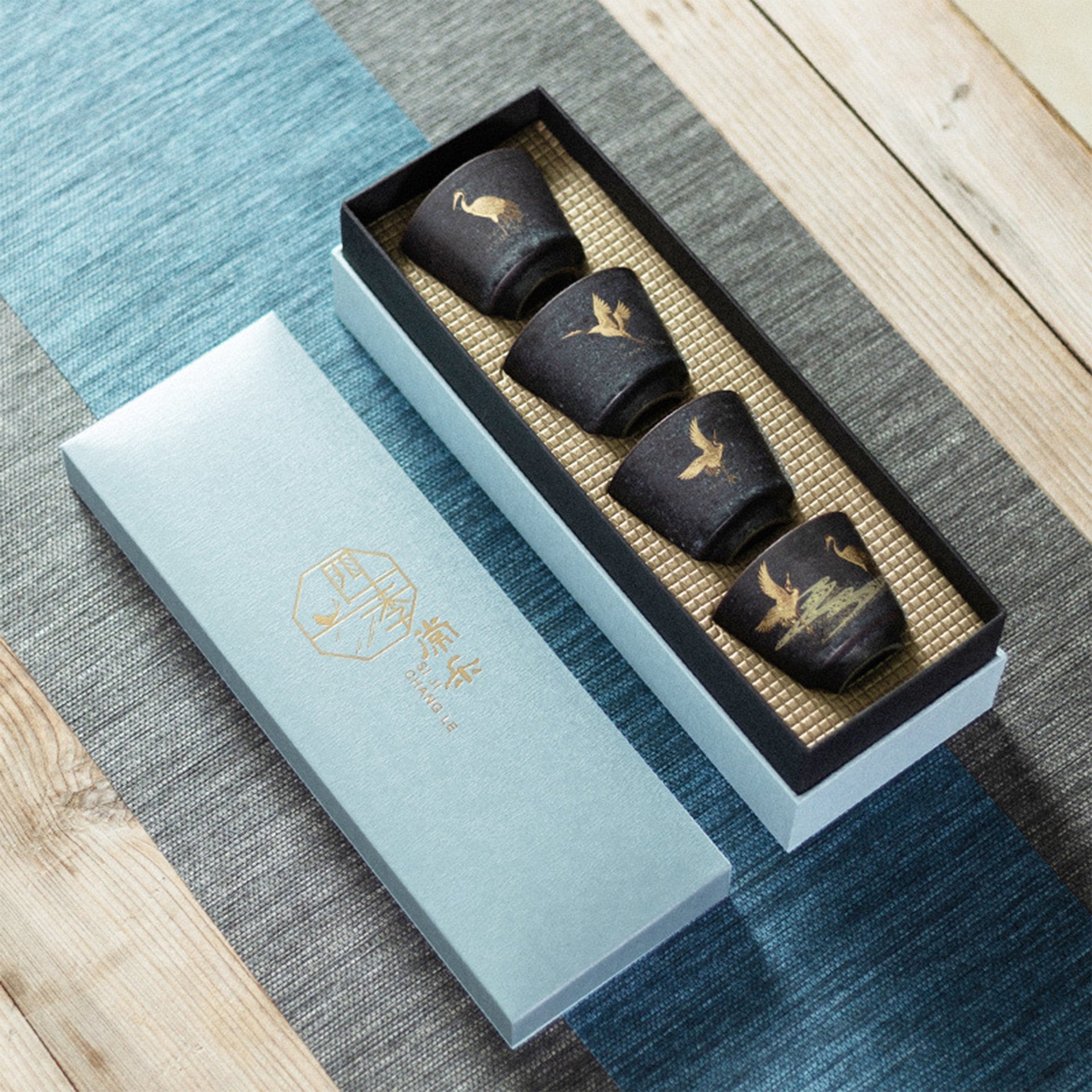 Tea set of four japanese black teacups with golden crane motif in a gift box.