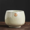 Creamy white Japanese teacup with a gold seal, on a wooden surface.