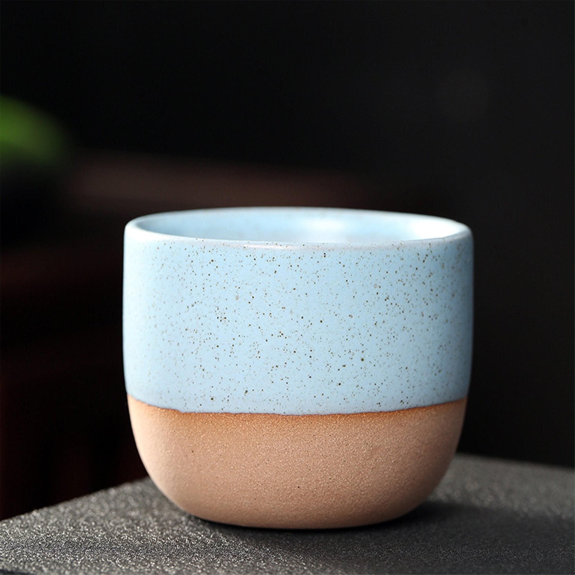 Light blue and beige two-tone ceramic teacup with speckles.