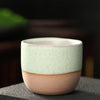 Light green and beige two-tone ceramic teacup with speckles.