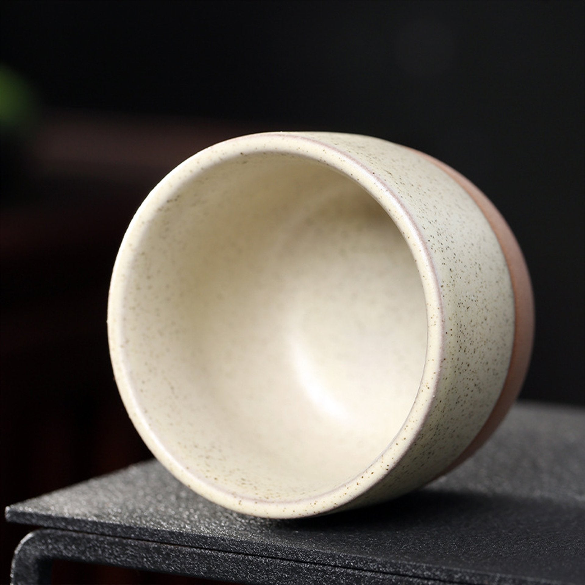 Angled view of a speckled beige Japanese ceramic teacup.
