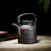 Large dark brown teapot with a complex symbol on side.