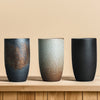 Three large ceramic cups displayed on a wooden surface, showcasing different textures and colors.