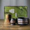 Matcha tea set packaging with a bamboo whisk, holder, scoop, and bowl displayed in front.