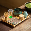 Complete Matcha tea set with whisk, bowl, scoop, holder, tea towel, tea caddy on a wooden tray.