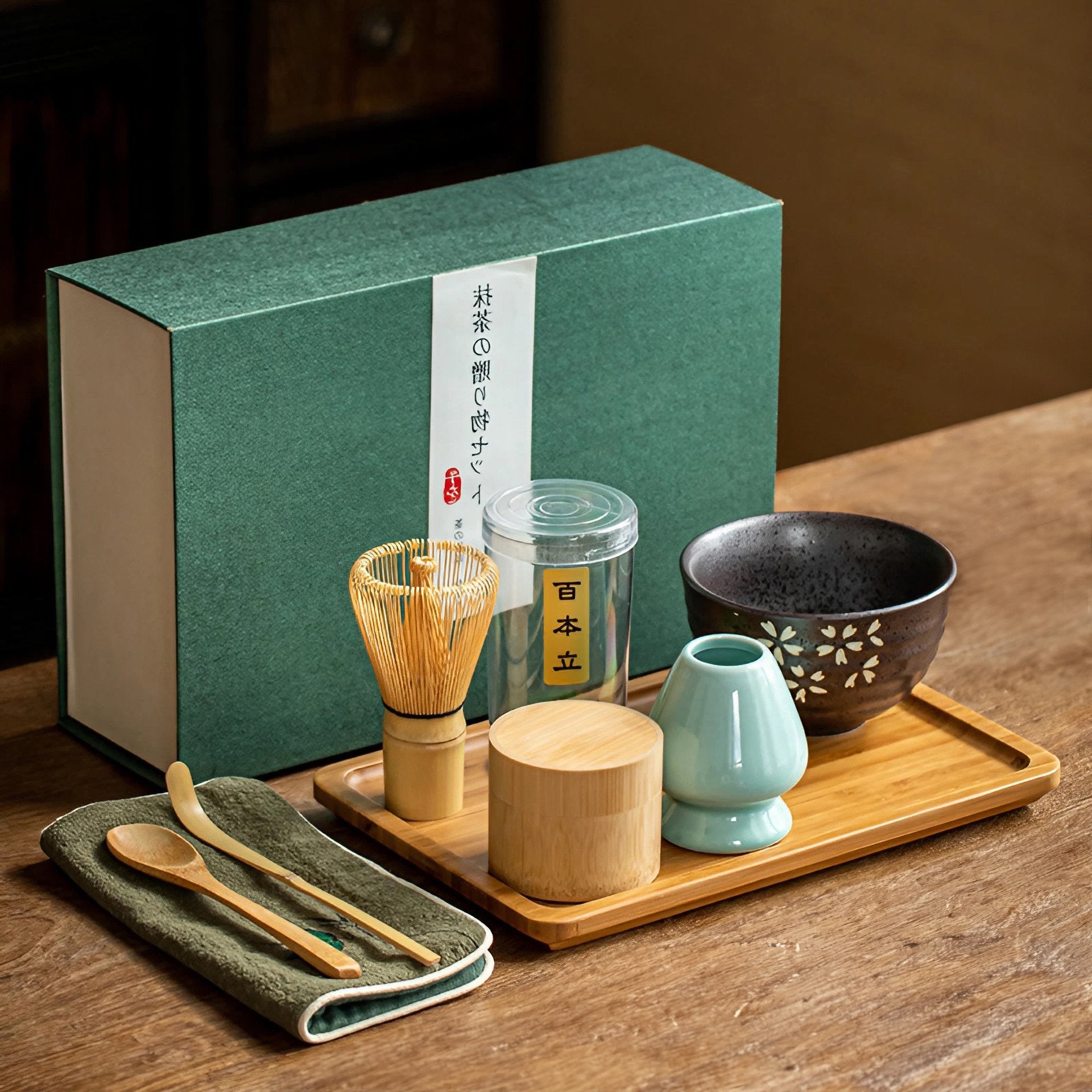 Complete Matcha tea set with a bamboo whisk, scoop, bowl, and whisk holder on a wooden tray, beside a boxed set.