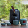 Travel tea set with green cups, pot, and black carrying case.