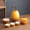 Orange teapot in a yellow case displayed on a wooden table.