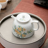 Floral porcelain teapot on tray, white with floral pattern.