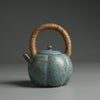 Textured blue teapot with a rustic look and fiber handle on a dark background.
