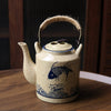 Vintage styled Japanese teapot with koi fish design on a wooden table.