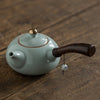 Side-handle teapot with a blue body and wooden handle on a wooden surface