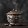 Artistic brown and silver plum teapot on a wooden stand, dark backdrop
