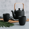 Modern black ceramic tea set with a bamboo handle on the teapot, set on a wooden tray with cups.