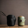  A black tea case and a green ceramic tea canister with a wooden lid on a wooden surface.