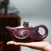 Hand holding a dark brown teapot lid, showing the inner detail.