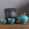 Teapot and cups displayed in front of open black zippered carrying case