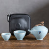 Teapot and cups displayed in front of open black zippered carrying case