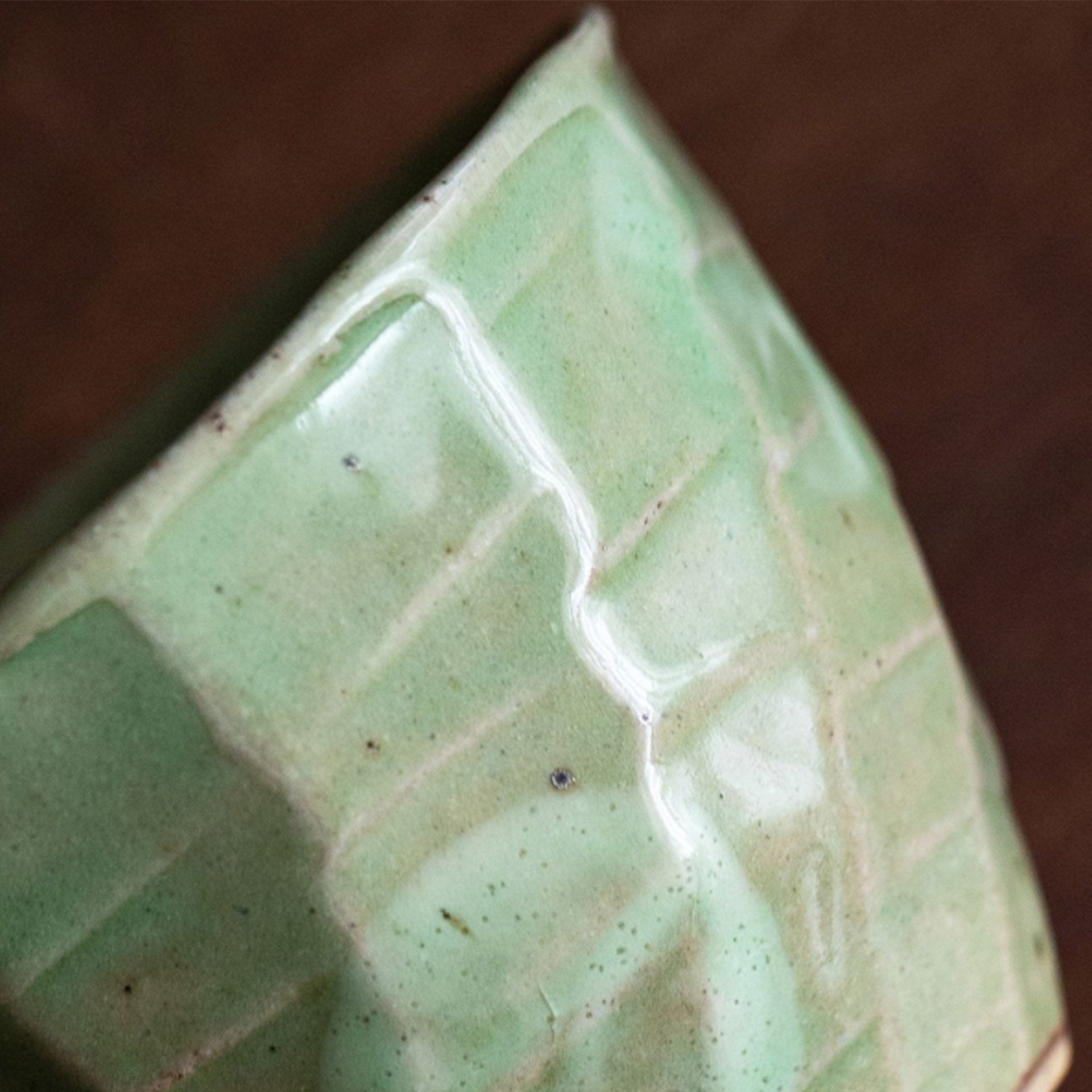 Close-up of a green glazed ceramic cup with geometric pattern