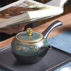 Yokade kyusu teapot on a tray with a blurred book in the background